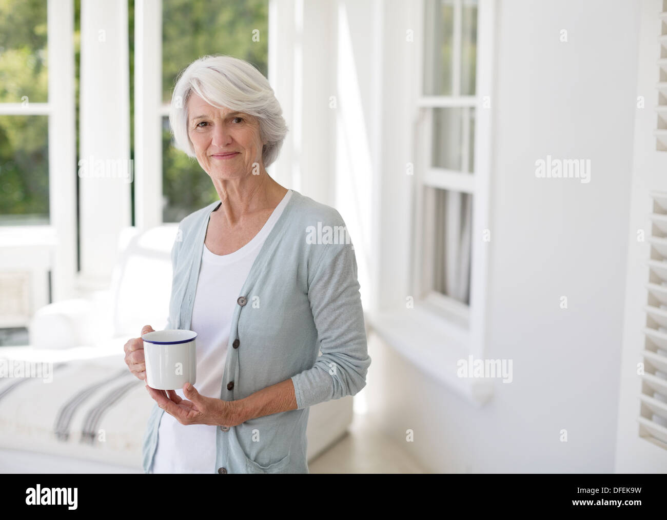 Senior donna azienda tazza di caffè nella sala sun Foto Stock