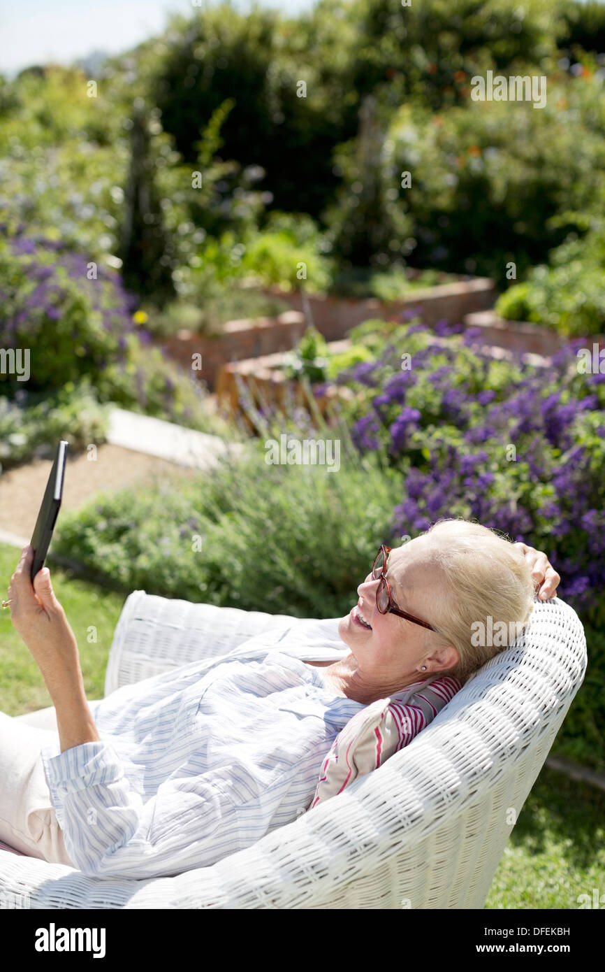 Senior donna utilizzando digitale compressa in giardino Foto Stock