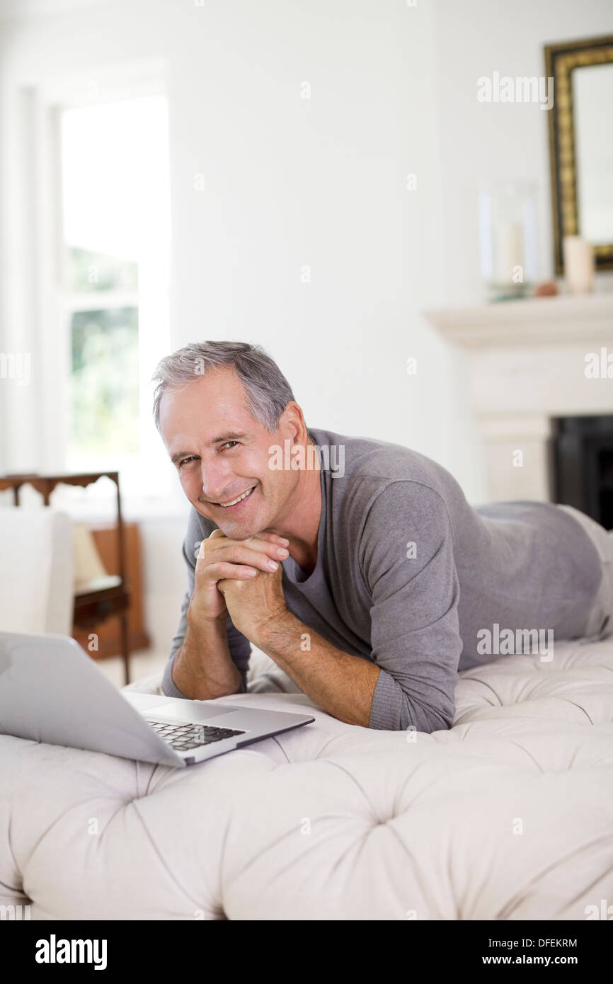 Senior uomo utilizzando laptop in livingroom Foto Stock