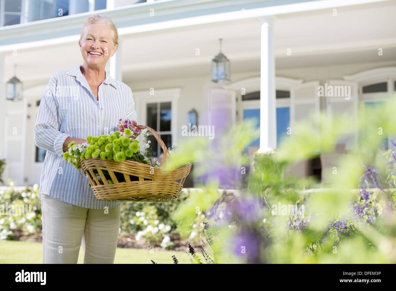 Ritratto di donna senior a caccia di fiori nel giardino Foto Stock