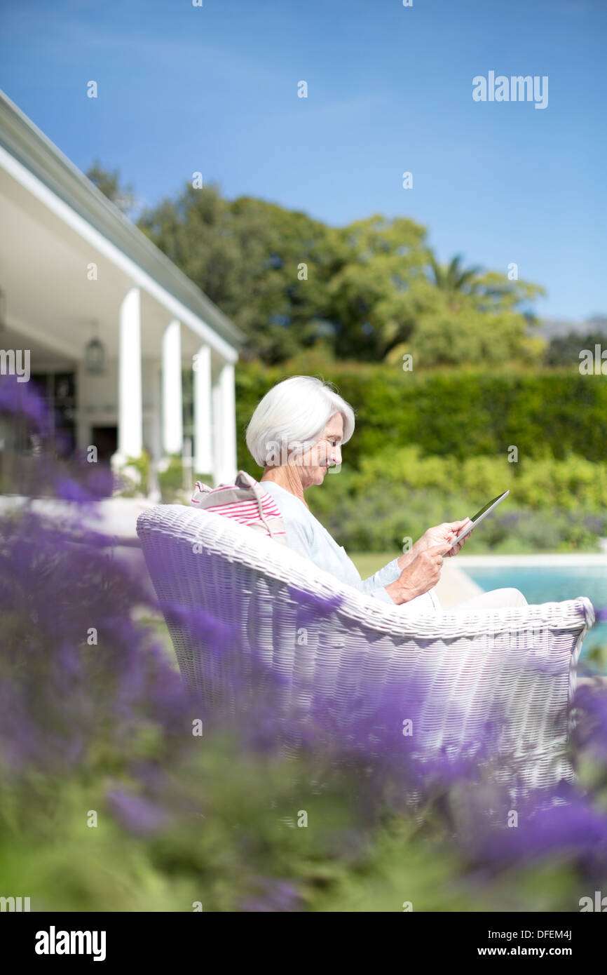 Senior donna utilizzando digitale compressa in giardino Foto Stock