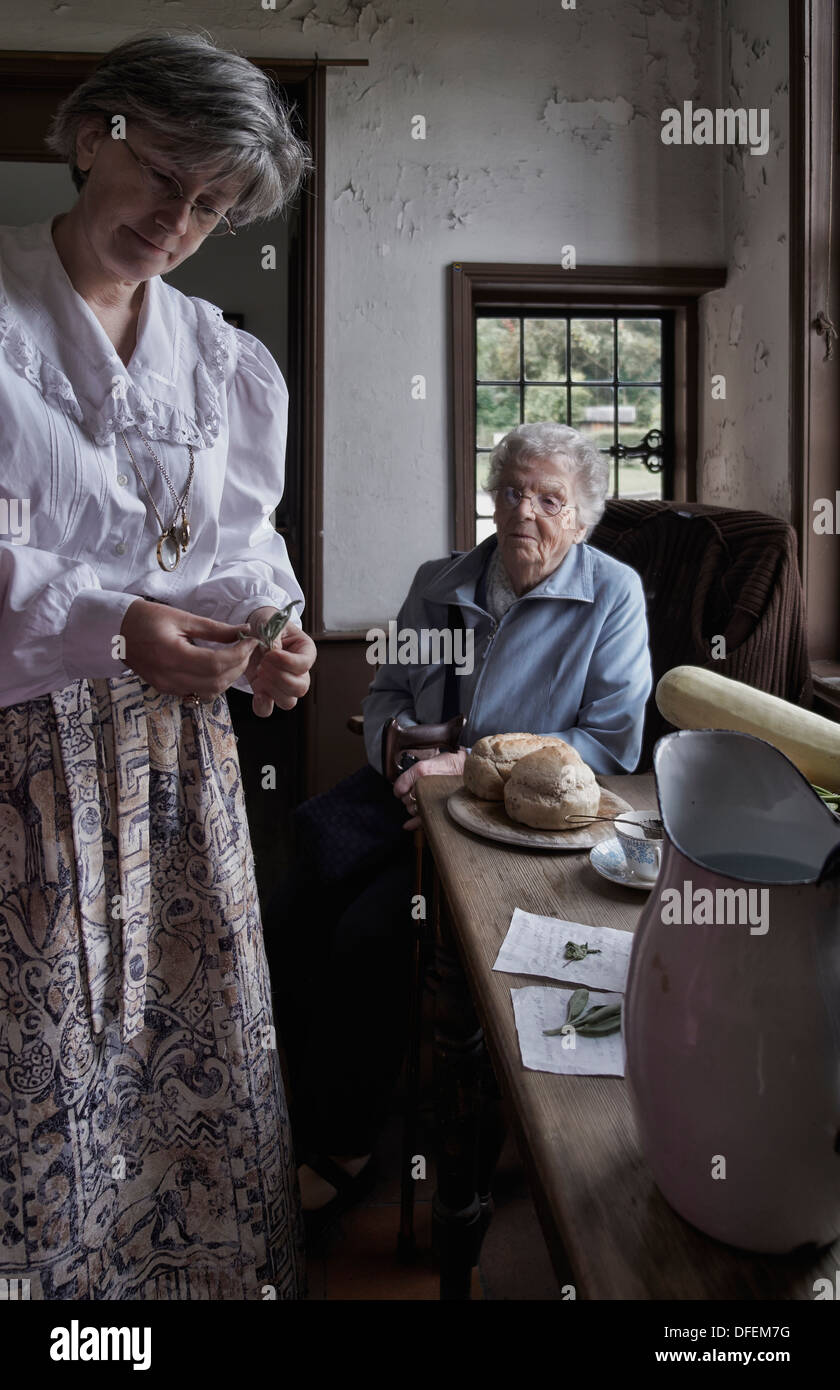 Black Country Museum con un'impiegata donna che mostra a un visitatore anziano i prodotti alimentari tradizionali risalenti all'inizio degli anni '1900 del 1800. Inghilterra Regno Unito Foto Stock