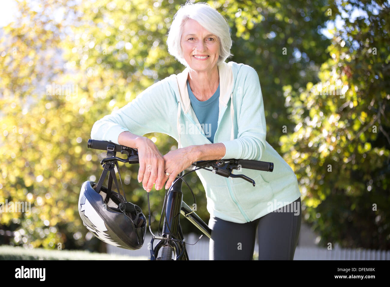 Ritratto di donna senior appoggiata sulla bicicletta Foto Stock