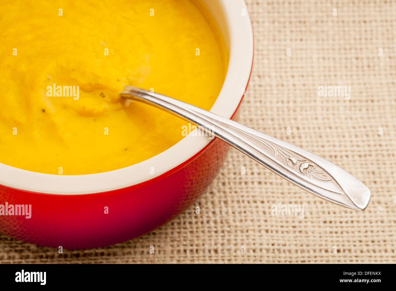 La carota minestra in crema in un recipiente di ceramica su tela lo sfondo Foto Stock