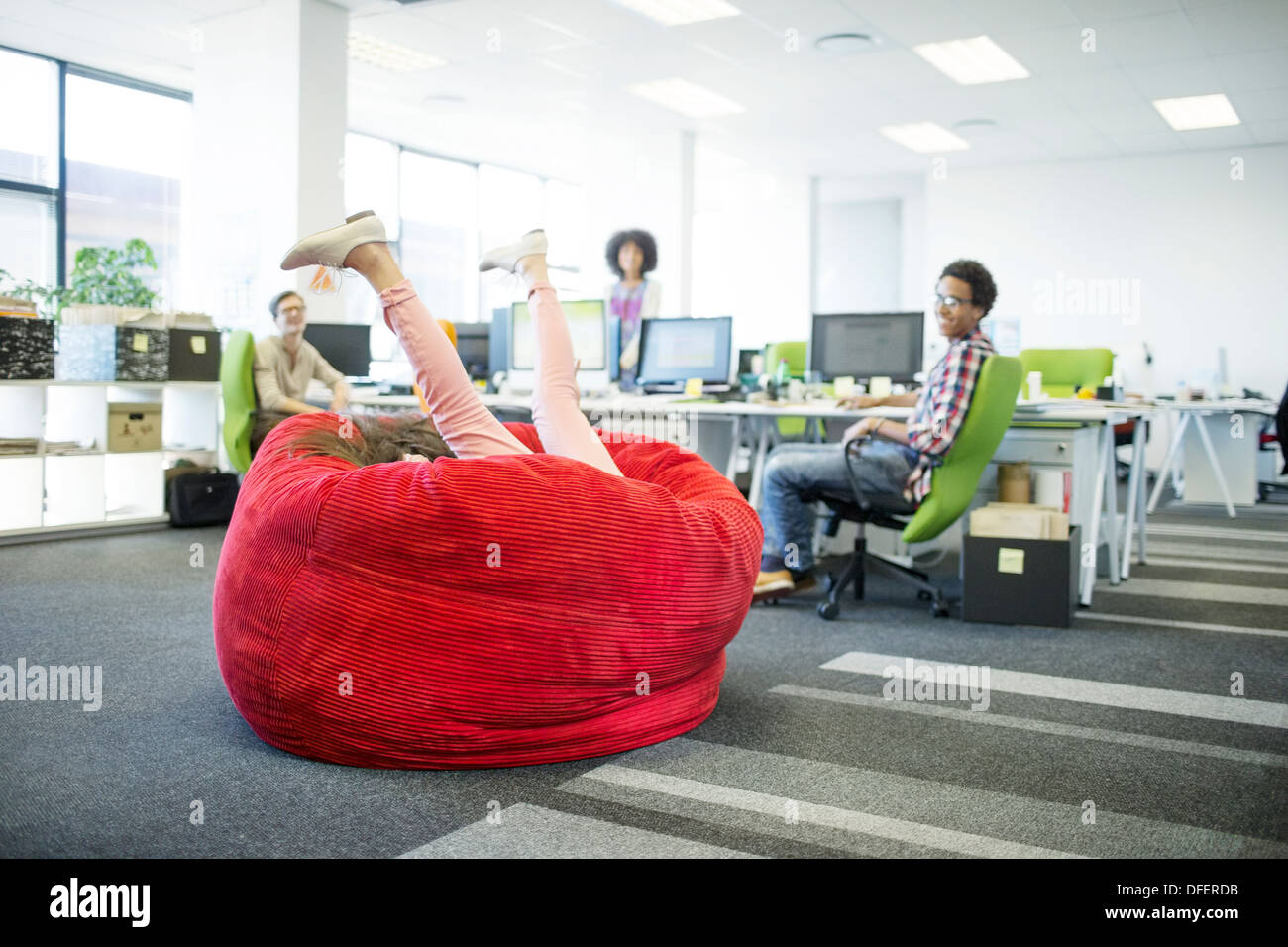 Imprenditrice giocando in beanbag chair in ufficio Foto Stock