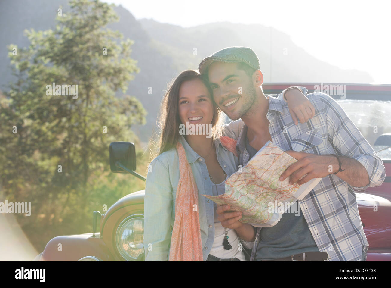 Coppia sorridente con mappa accanto a sport utility vehicle Foto Stock
