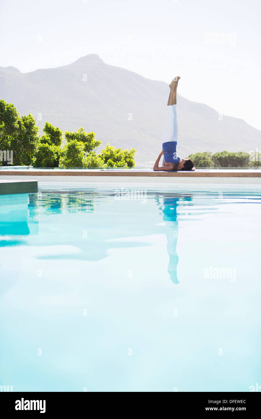 La donna a praticare yoga a bordo piscina Foto Stock