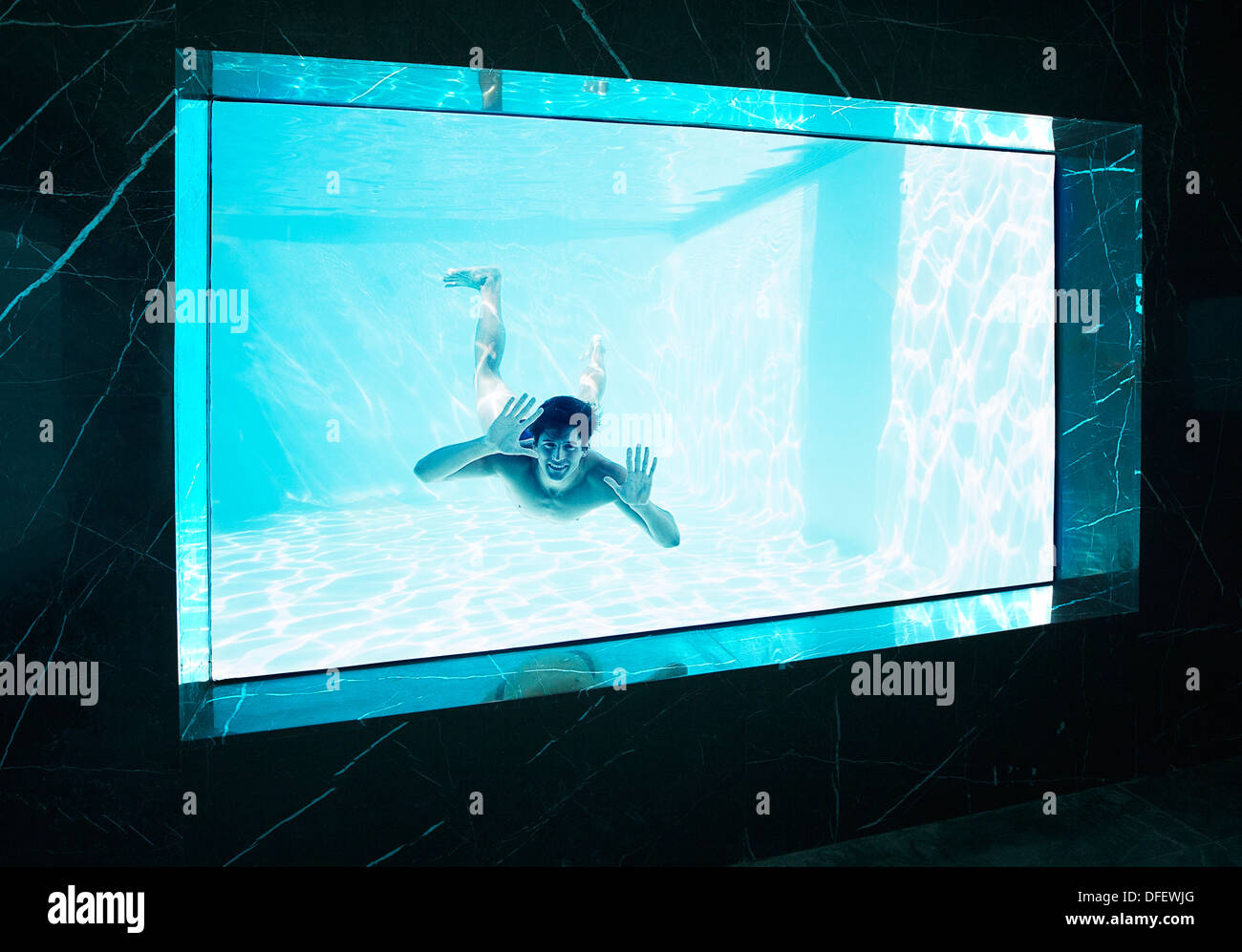 Uomo che guarda attraverso la finestra sott'acqua in piscina Foto Stock