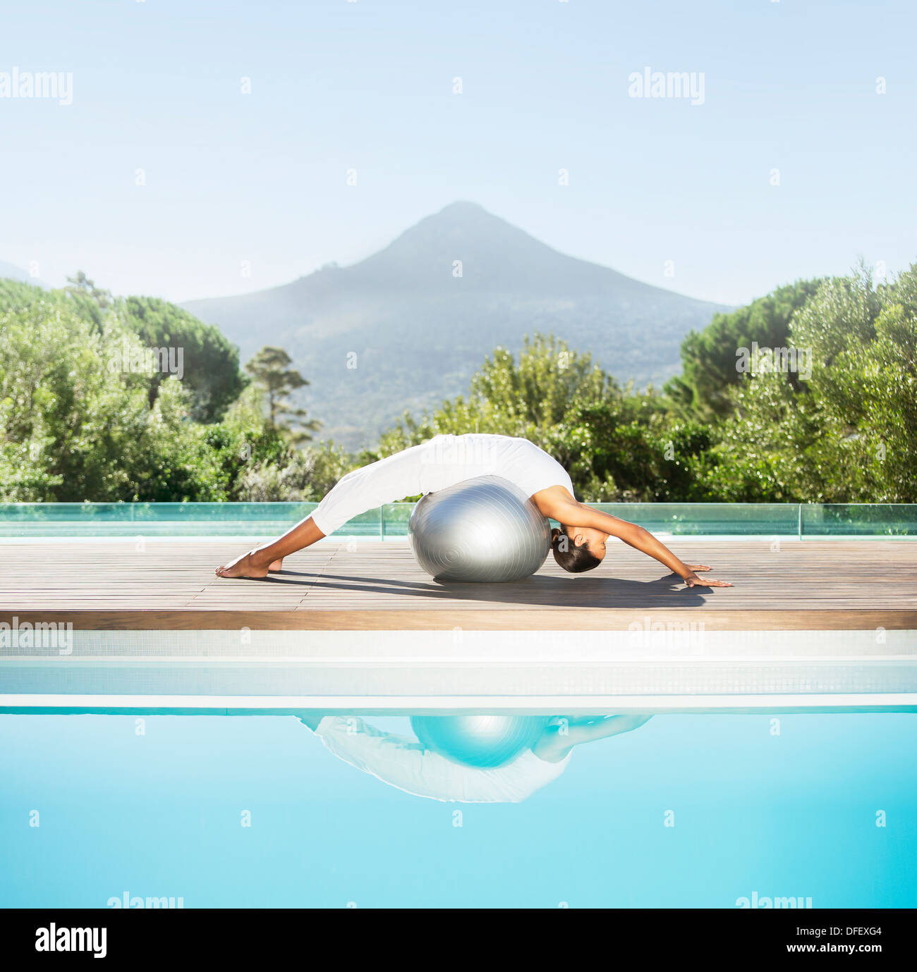 Donna stretching over sfera fitness a bordo piscina Foto Stock