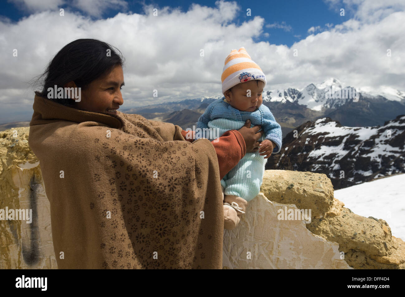 Madre boliviana tenendo il suo bambino neonato a 5421 metri (17,785 ft) summit di Chacaltaya stazione, come una tradizione locale, nei pressi di La Paz in Bolivia Foto Stock