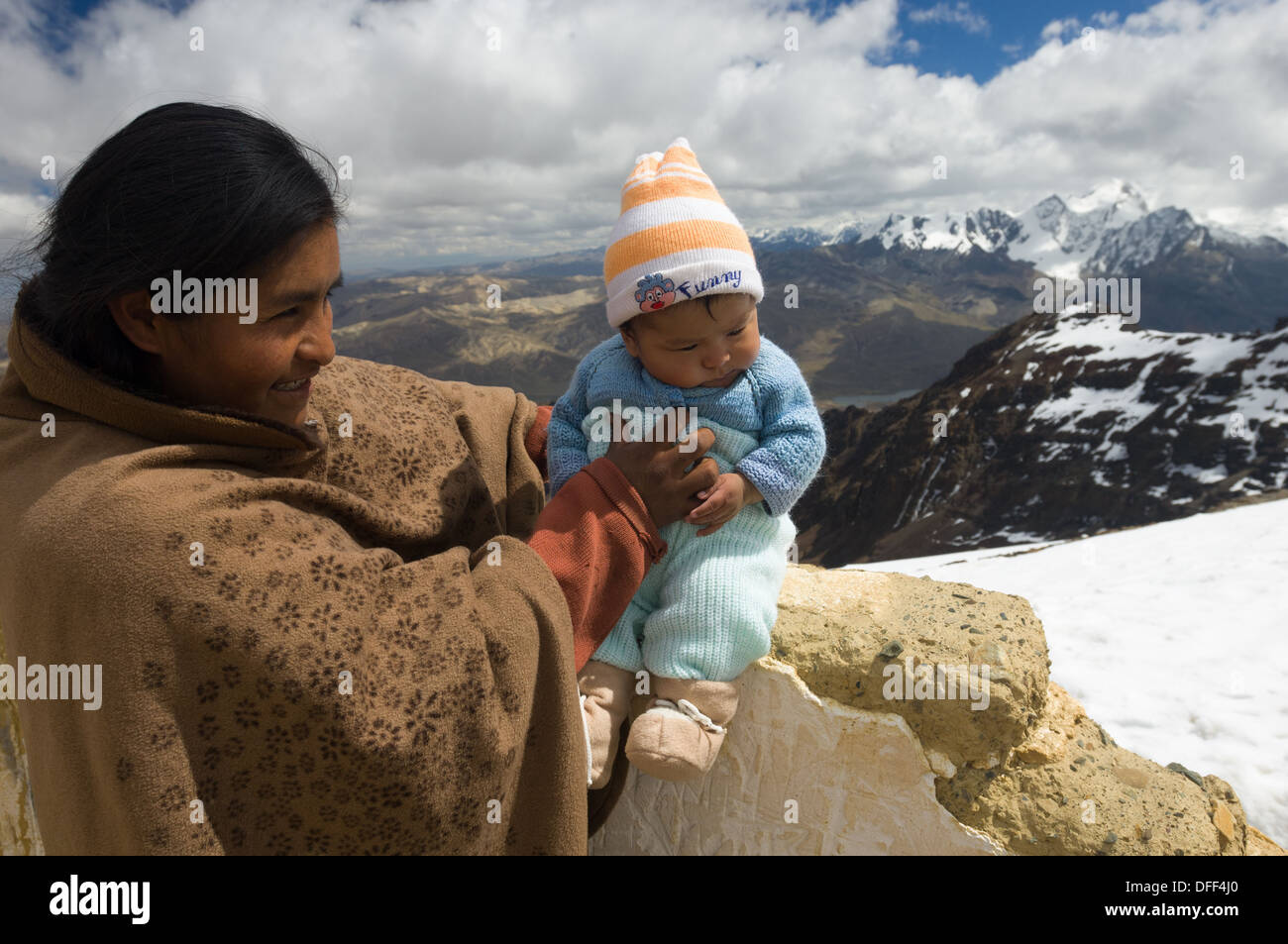Madre boliviana tenendo il suo bambino neonato a 5421 metri (17,785 ft) summit di Chacaltaya stazione, come una tradizione locale, nei pressi di La Paz in Bolivia Foto Stock