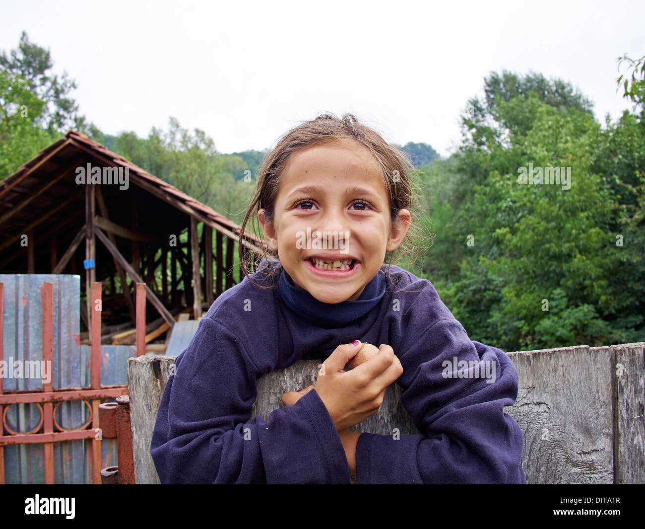 Zingaro giovane ragazza sorridente da una recinzione; Pârâu de Vale, Godineşti, Gorj, Romania,UE. Foto Stock