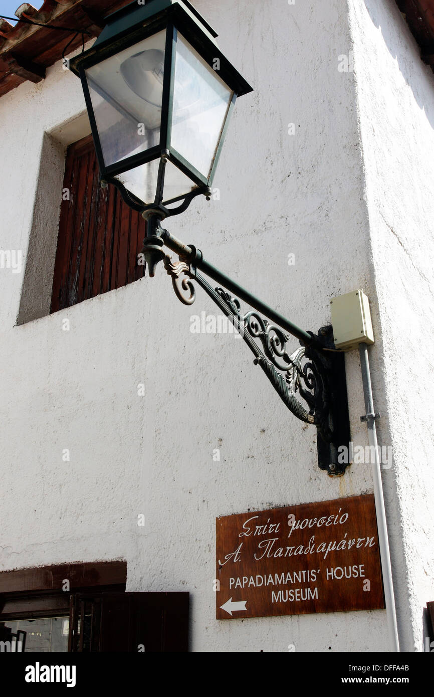 Una lampada a parete a Skiathos città sopra un segno indirizzare i visitatori alla casa del famoso poeta greco Alexandros Papadiamantis Foto Stock