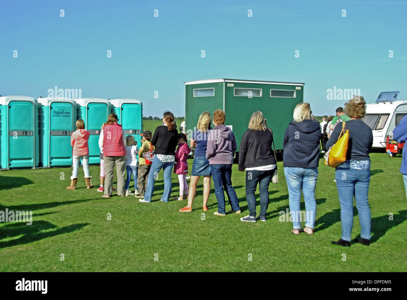La gente in coda per i bagni portatili a al di fuori sede Foto Stock La gente in coda per i bagni portatili a al di fuori sede Foto Stock