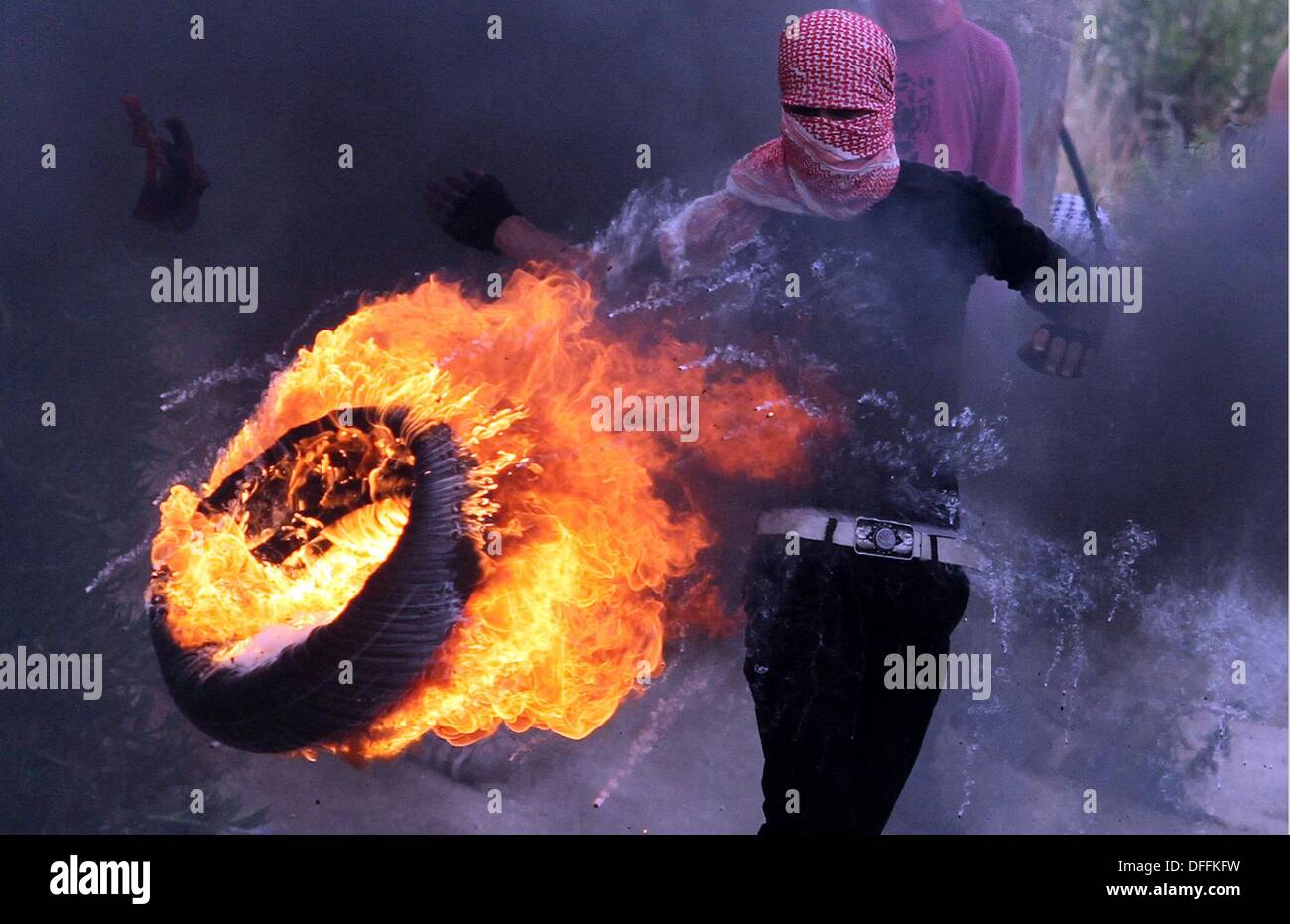 Ramallah, West Bank. 15 Maggio, 2013. Un manifestante palestinese calci un ardente pneumatico verso forze di sicurezza israeliane durante gli scontri per contrassegnare la Nakba esterno giorno Ofer carcere militare. I palestinesi si sono scontrati con le forze israeliane nei territori occupati della Cisgiordania e a Gerusalemme Est mercoledì durante le dimostrazioni per contrassegnare 65 anni dal 'La Nakba'. © Issam Rimawi APA/images/ZUMAPRESS.com/Alamy Live News Foto Stock