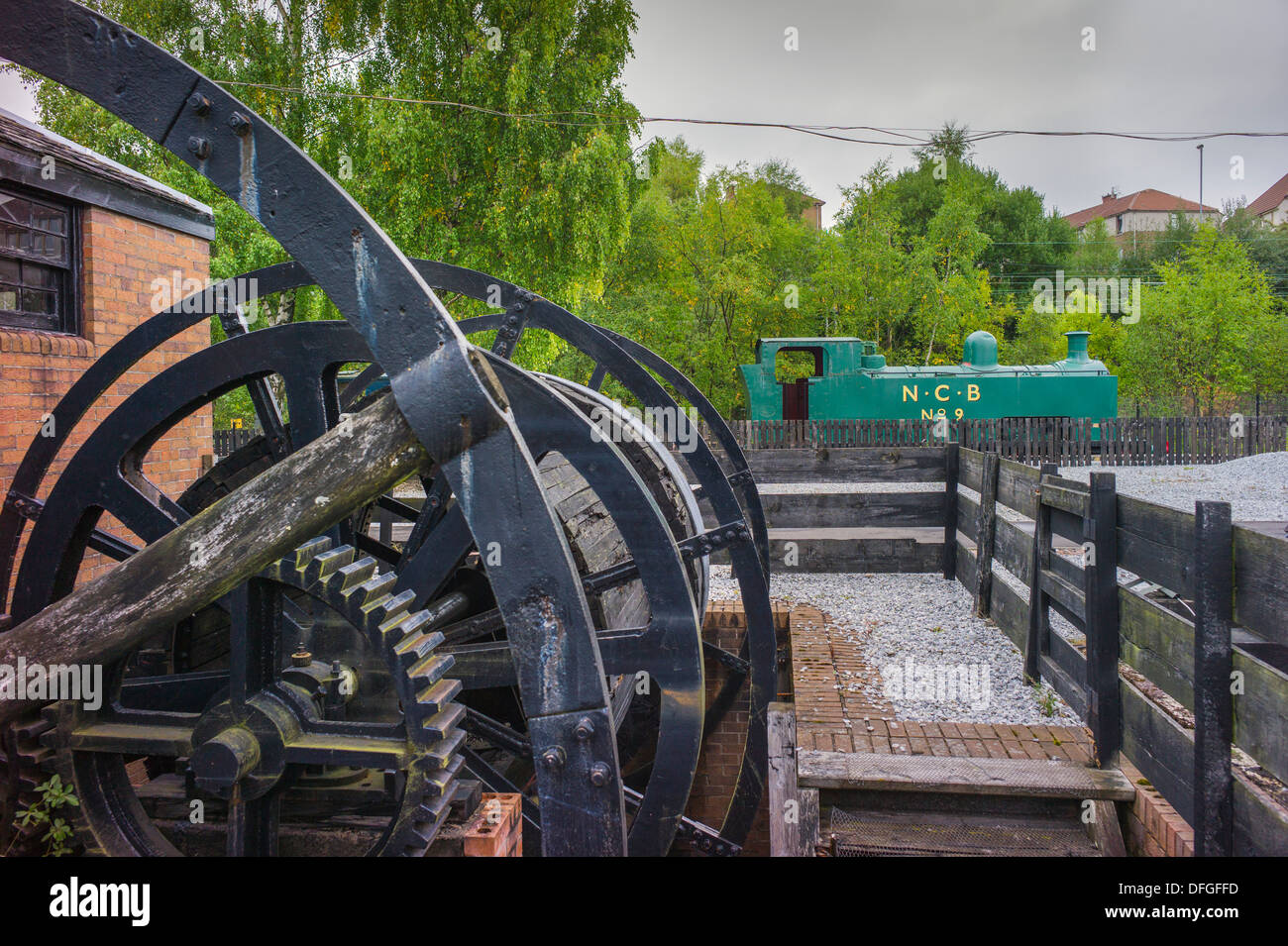 Una ricreazione di un piccolo pozzo minerario testa ingranaggio di avvolgimento in primo piano e un vecchio N.C.B. locomotiva di smistamento in background Foto Stock