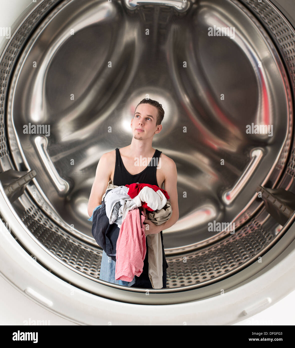 Immagine concettuale del giovane uomo confuso azienda servizio lavanderia all'interno di una lavatrice Foto Stock