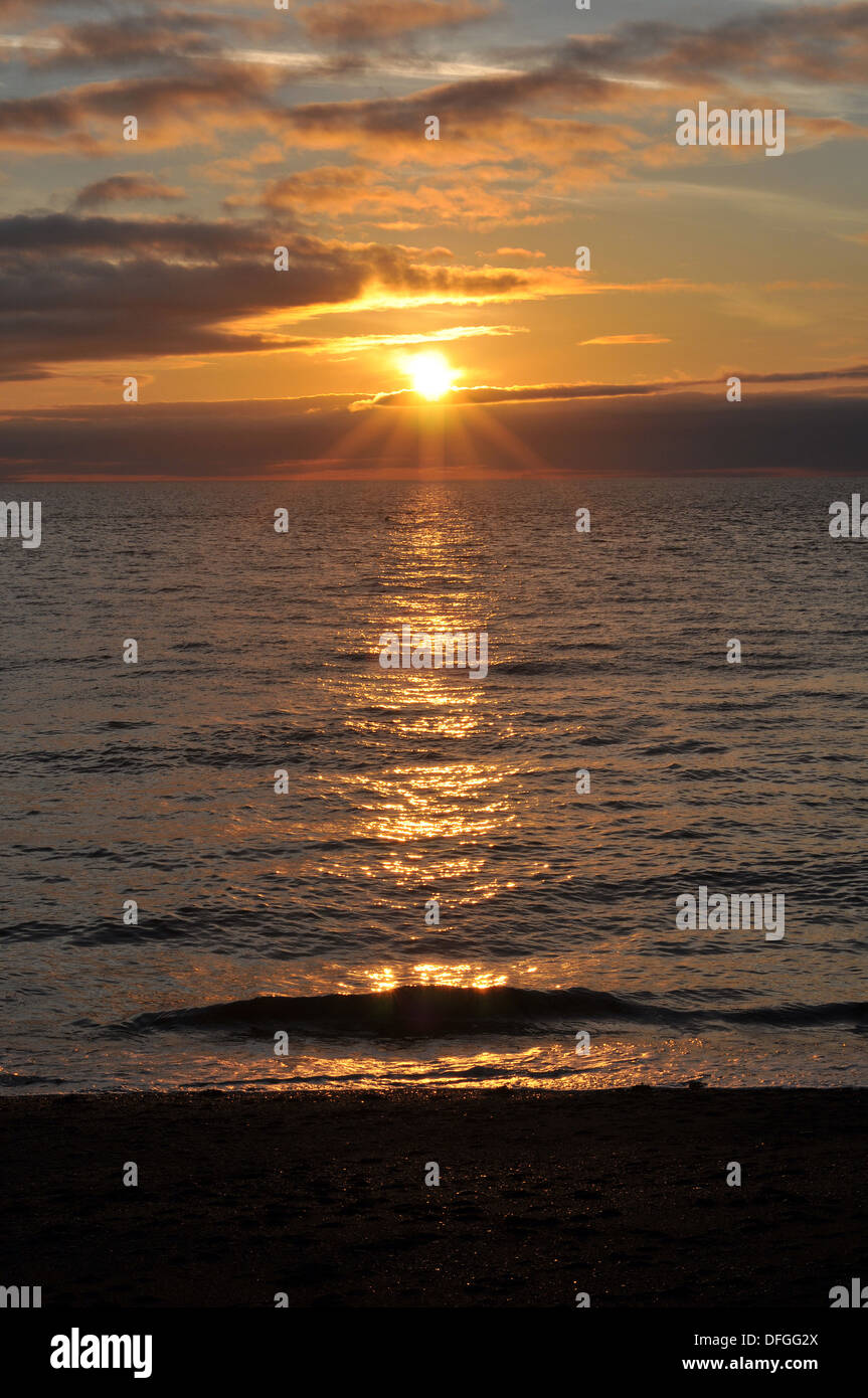 La sera di settembre sun lascia una scia di luce su Cardigan Bay, visto dal lungomare di Aberystwyth, Wales, Regno Unito Foto Stock