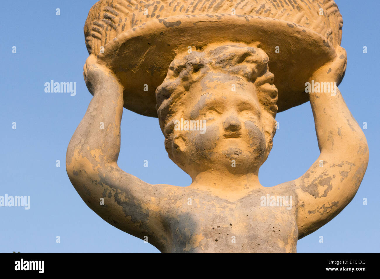 Scultura in terracotta di un bambino che porta un cesto Foto Stock