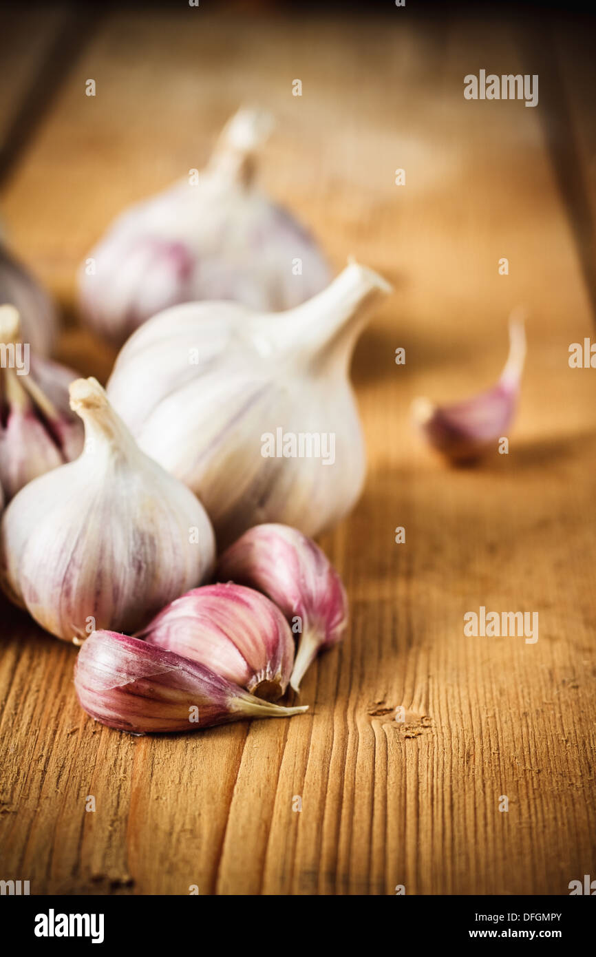 Bianco aglio crudo su tavola in legno sfondo scrivania. Organici di aglio intero e chiodi di garofano Foto Stock