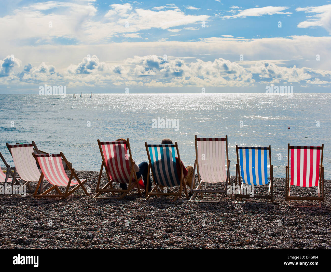 Due persone sedute a sdraio guardando il mare dalla spiaggia di birra Devon England Foto Stock