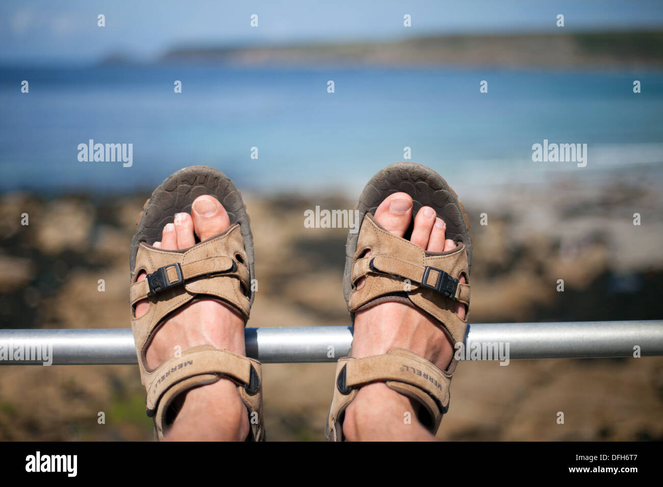 Piedi indossa sandali sulla ringhiera Sennen Cove Cornwall, vacanze Estate, Regno Unito Foto Stock