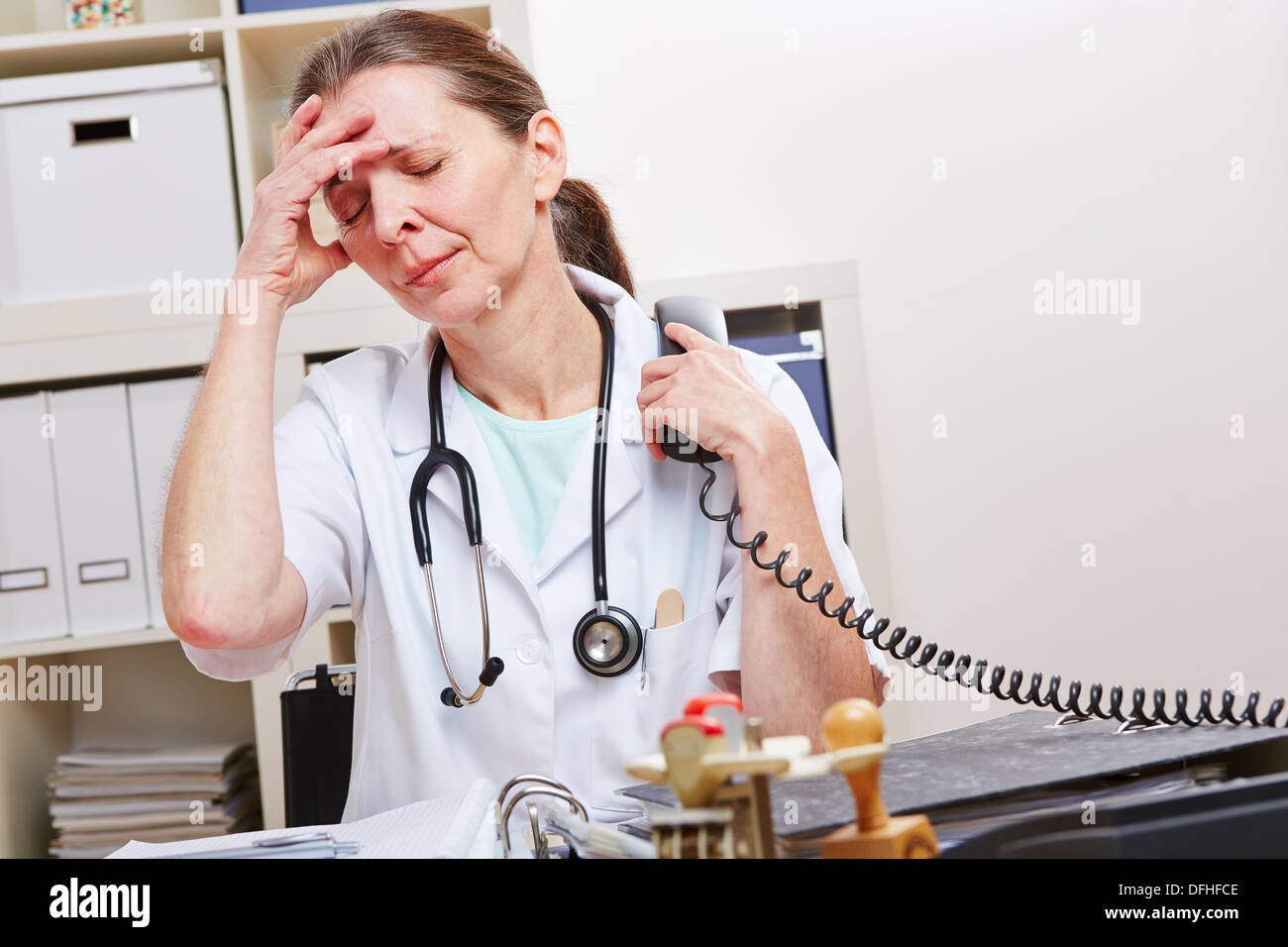 Medico con burnout snydrome in ufficio presso il telefono Foto Stock
