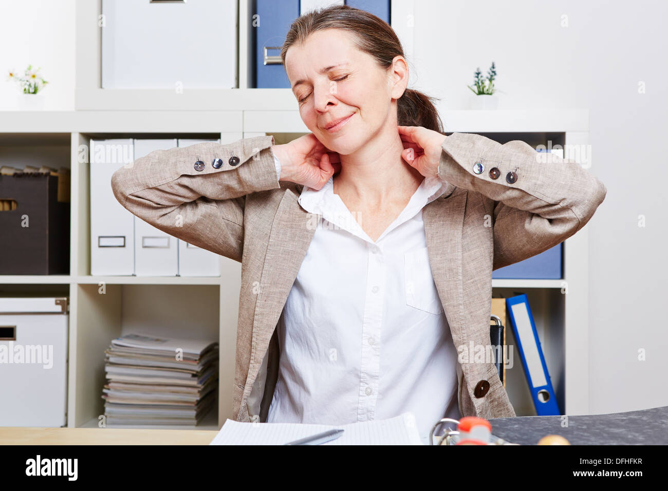 Senior business donna con dolore il massaggio al collo nel suo ufficio Foto Stock