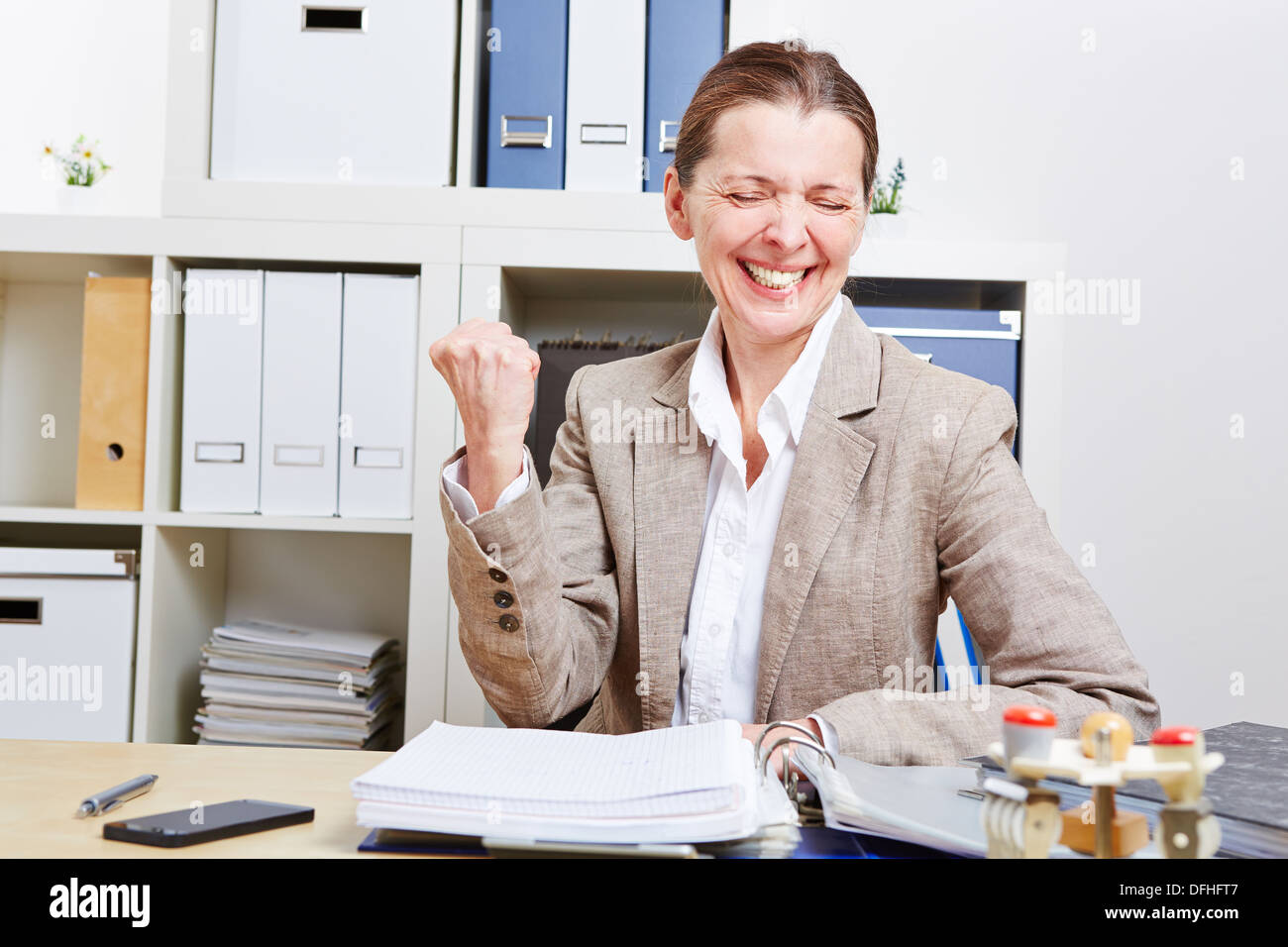 Il tifo senior business donna clenching il suo pugno in ufficio Foto Stock
