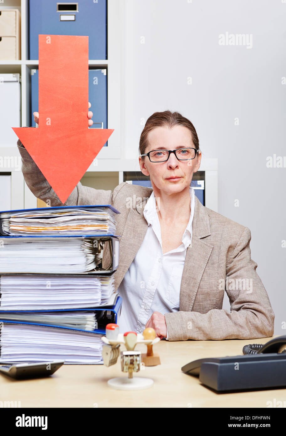 Strict business donna nel suo ufficio freccia alla pila di file Foto Stock