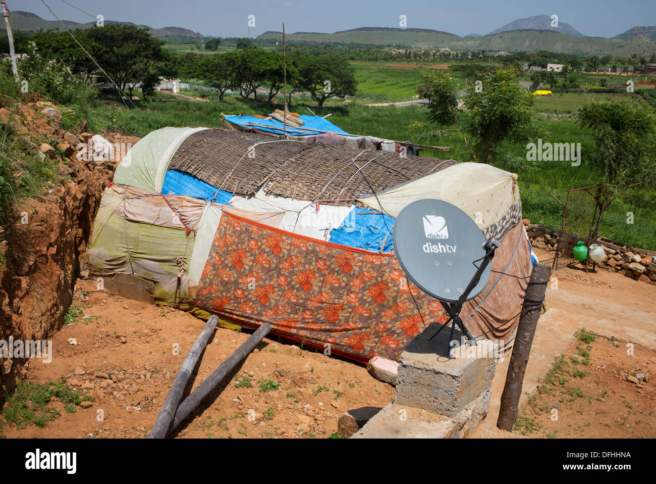 TV satellitare al di fuori di un ambiente rurale di casta inferiore famiglie indiano tenda. Andhra Pradesh, India Foto Stock
