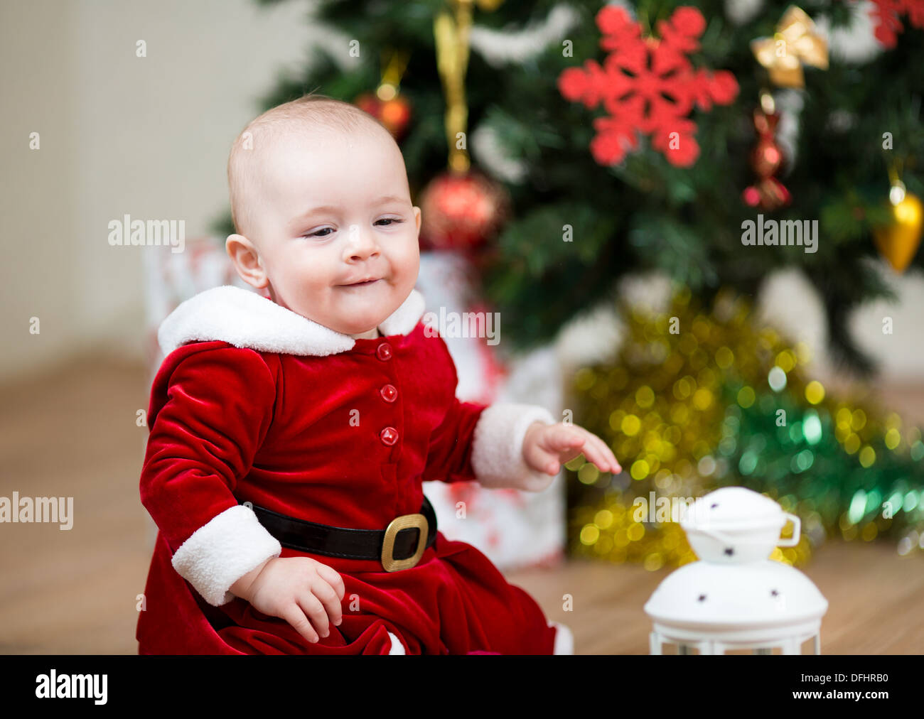Piuttosto bambino seduto di fronte ad albero di Natale a casa Foto Stock
