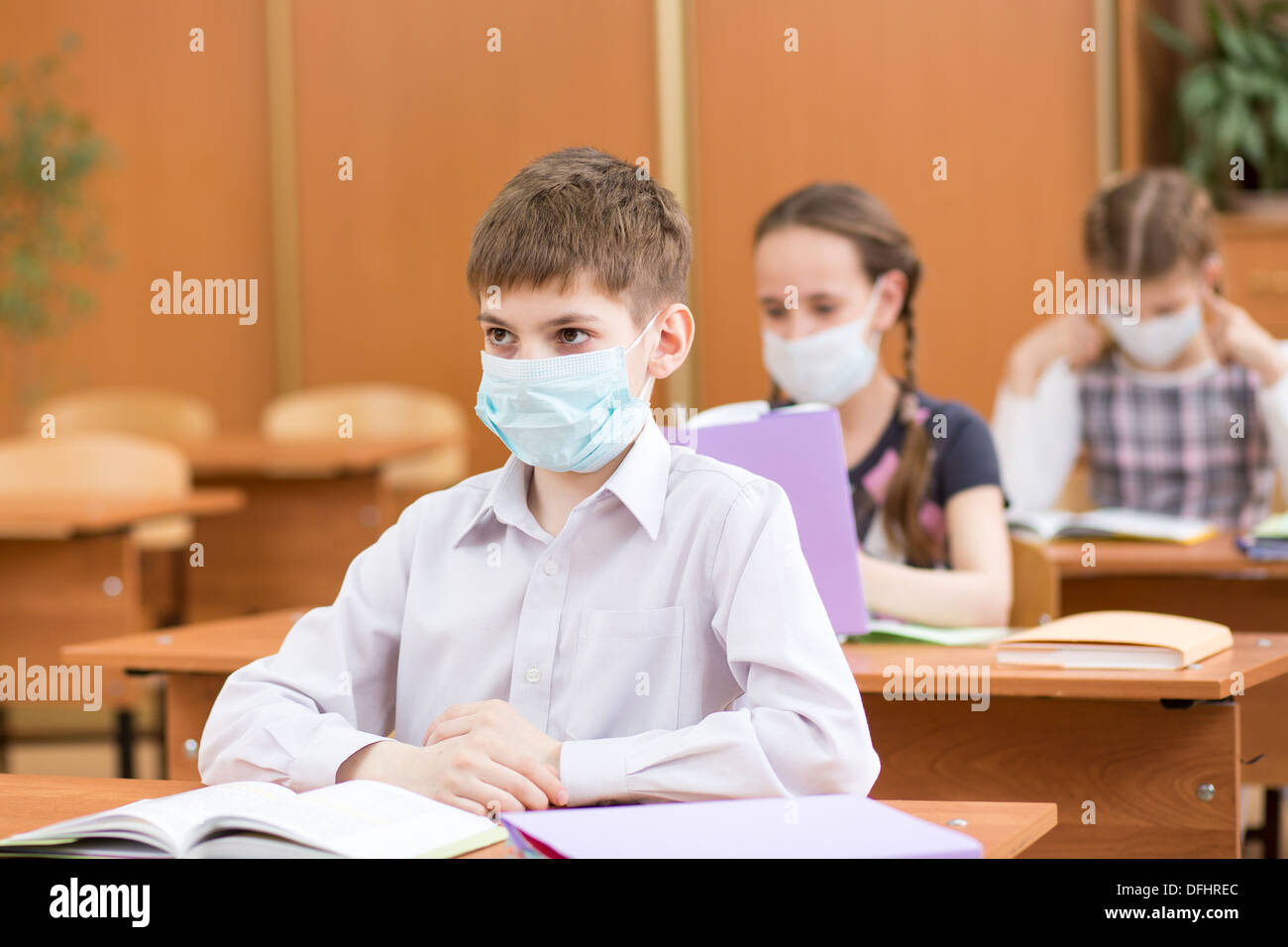 Gli alunni con maschera di protezione contro virus influenzale a lezione Foto Stock