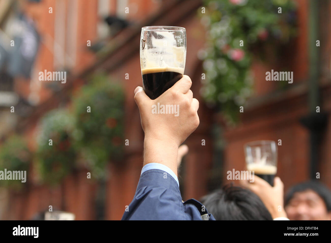 Una mano tiene una pinta di Guinness in aria durante la Arthur's celebrazioni della Giornata nel centro della città di Dublino. Foto Stock