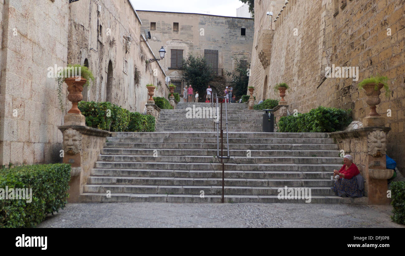 Donna locali in costume tradizionale seduta sulla scalinata tra mura storiche, Palma di Maiorca, SPAGNA Foto Stock