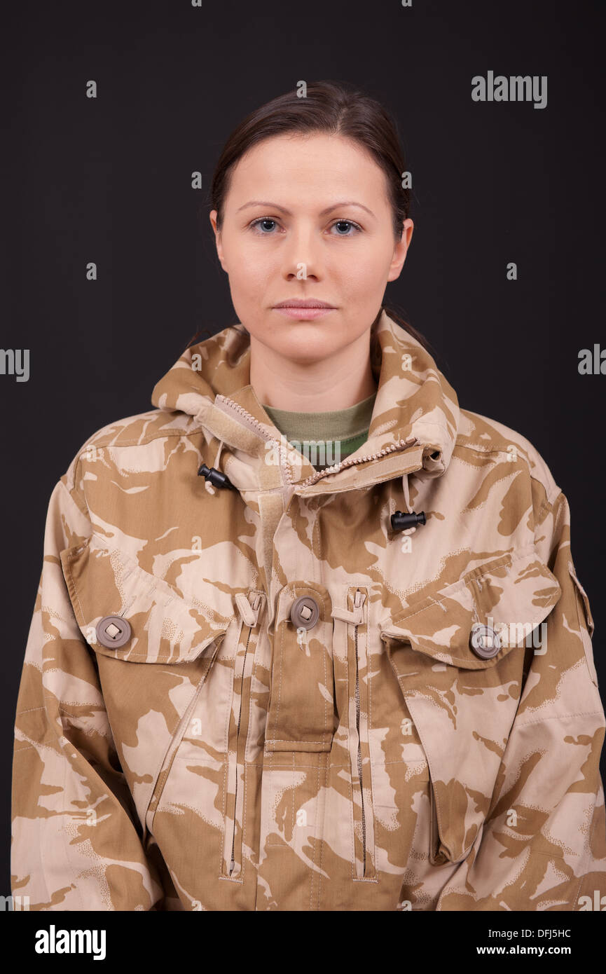 Ritratto di un soldato di sesso femminile contro uno sfondo nero. Soldato indossa militare inglese desert camouflage uniforme. Foto Stock