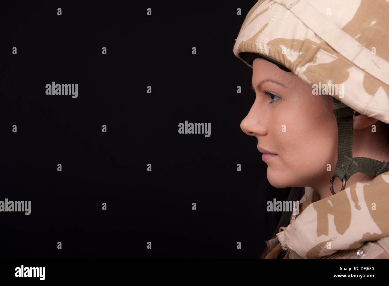 Giovani donne soldato indossando militare inglese desert camouflage uniforme, contro uno sfondo nero. Foto Stock