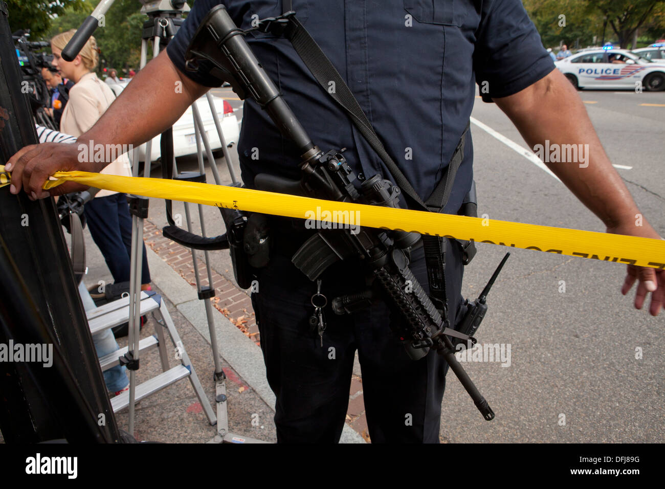 Poliziotto che trasportano un semi-auto fucile mettendo a linea di polizia il nastro a una scena del crimine - Washington DC, Stati Uniti d'America Foto Stock