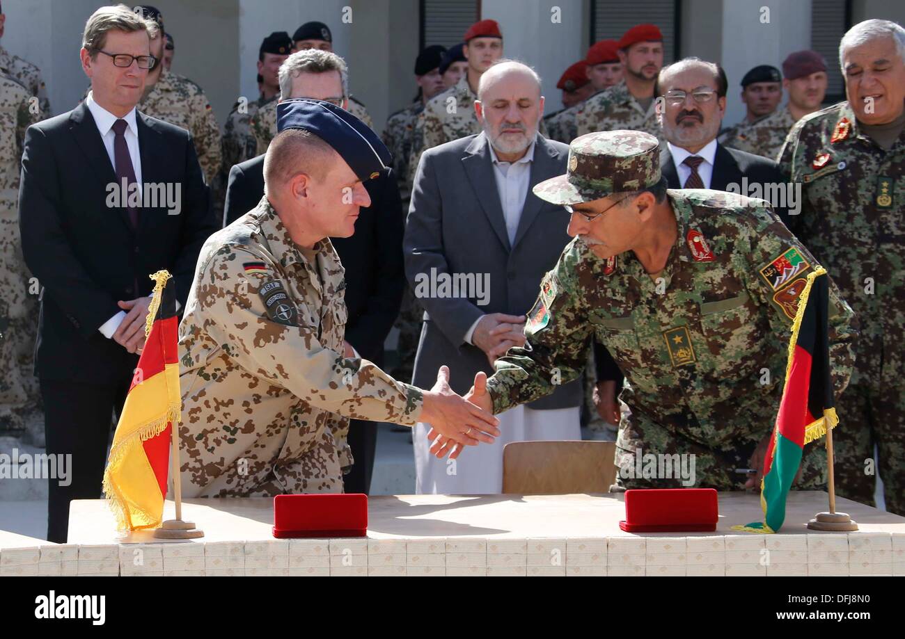 Il Ministro degli esteri tedesco Guido Westerwelle (bancata posteriore L-2nd R), Ministro tedesco della difesa Thomas de Maiziere afgano, il ministro degli Interni Mohammad Omar Daudzai, afgano e il Vice Ministro della difesa Enayatullah Nazari guarda come tedesco e esercito afghano alti funzionari si stringono la mano durante la cerimonia di passaggio di un tedesco di base per l'Afghanistan forze armate a Kunduz Ottobre 6, 2013. Soldati della contingenza tedesco della Forza internazionale di assistenza alla sicurezza (ISAF) ha ritirato dalla loro base a Kunduz e il campo sarà utilizzato dall'Esercito nazionale afgano e la nazionale afghano di ordine civile di polizia (ANC Foto Stock