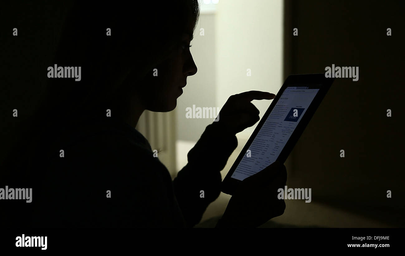 Silhouette di una giovane ragazza utilizzando una tavoletta digitale con una porta aperta. Foto Stock