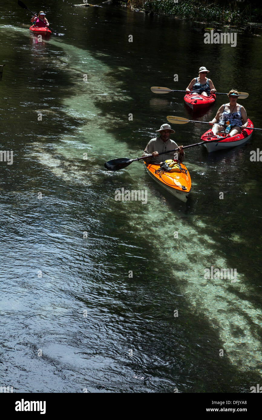 Uomini donne paddling arancione, rosso, bianco e blu kayak verso il basso le molle blu esegui. Foto Stock