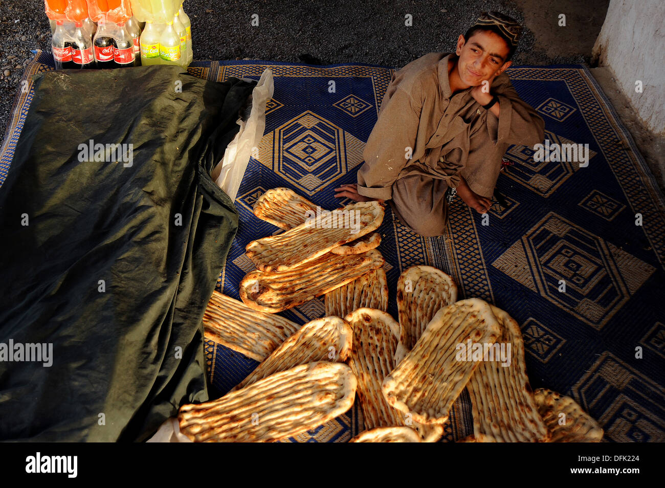 Zahir Najibullah attende pazientemente per i clienti che desiderano acquistare afgane tradizionali pane Naan al suo stallo stradale Giugno 7, 2010 in un piccolo villaggio vicino a Kandahar, Afghanistan. Foto Stock