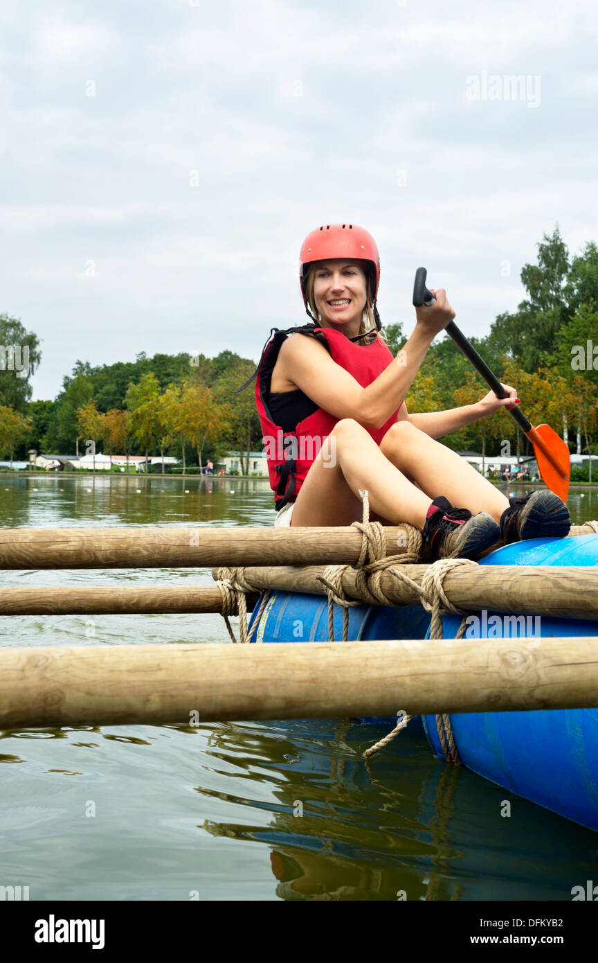 Un sorridente giovane donna rafting verso un fiume Foto Stock
