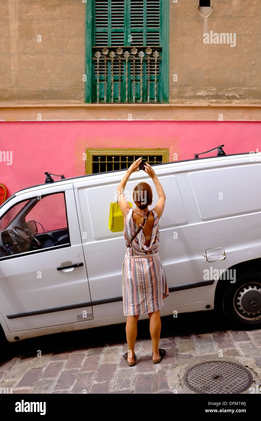 Un turista femminile in Maiorca fotografie una finestra ritagliata con il suo telefono Foto Stock