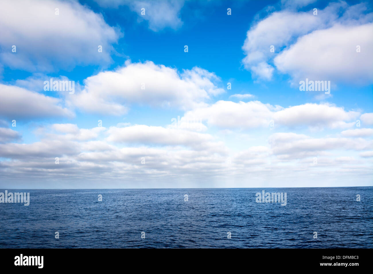 Un puffy bianco, cielo nuvoloso sopra l'oceano durante una giornata splendente. Foto Stock