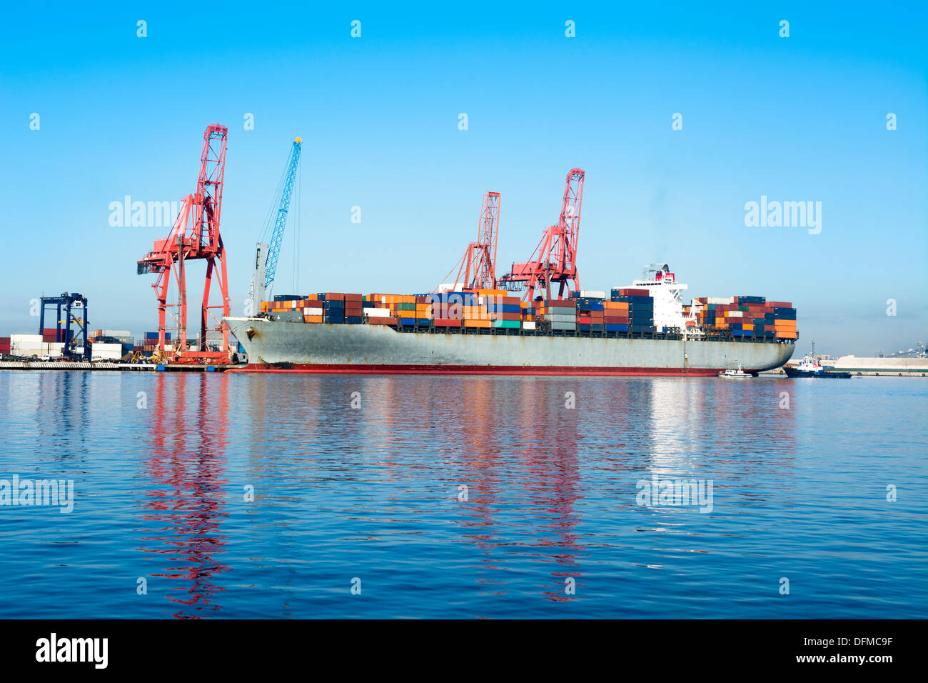 Un cargo freighter con colorati ai contenitori di carico essendo caricati per il trasporto internazionale Foto Stock