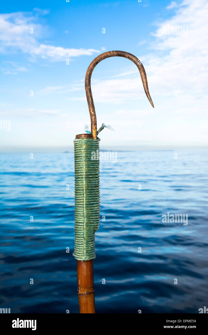 Un vecchio arrugginito pesca sportiva gaff contro un cielo blu e l'oceano. Foto Stock