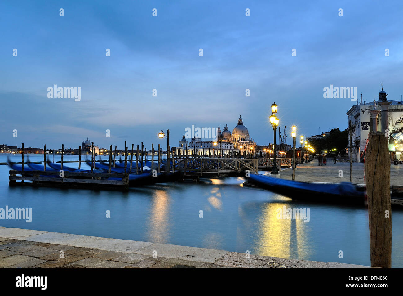Bella immagine catturata durante le ore di colore blu a Venezia, il primo piano possiamo vedere le tipiche gondole veneziane ormeggiata presso il molo, Foto Stock