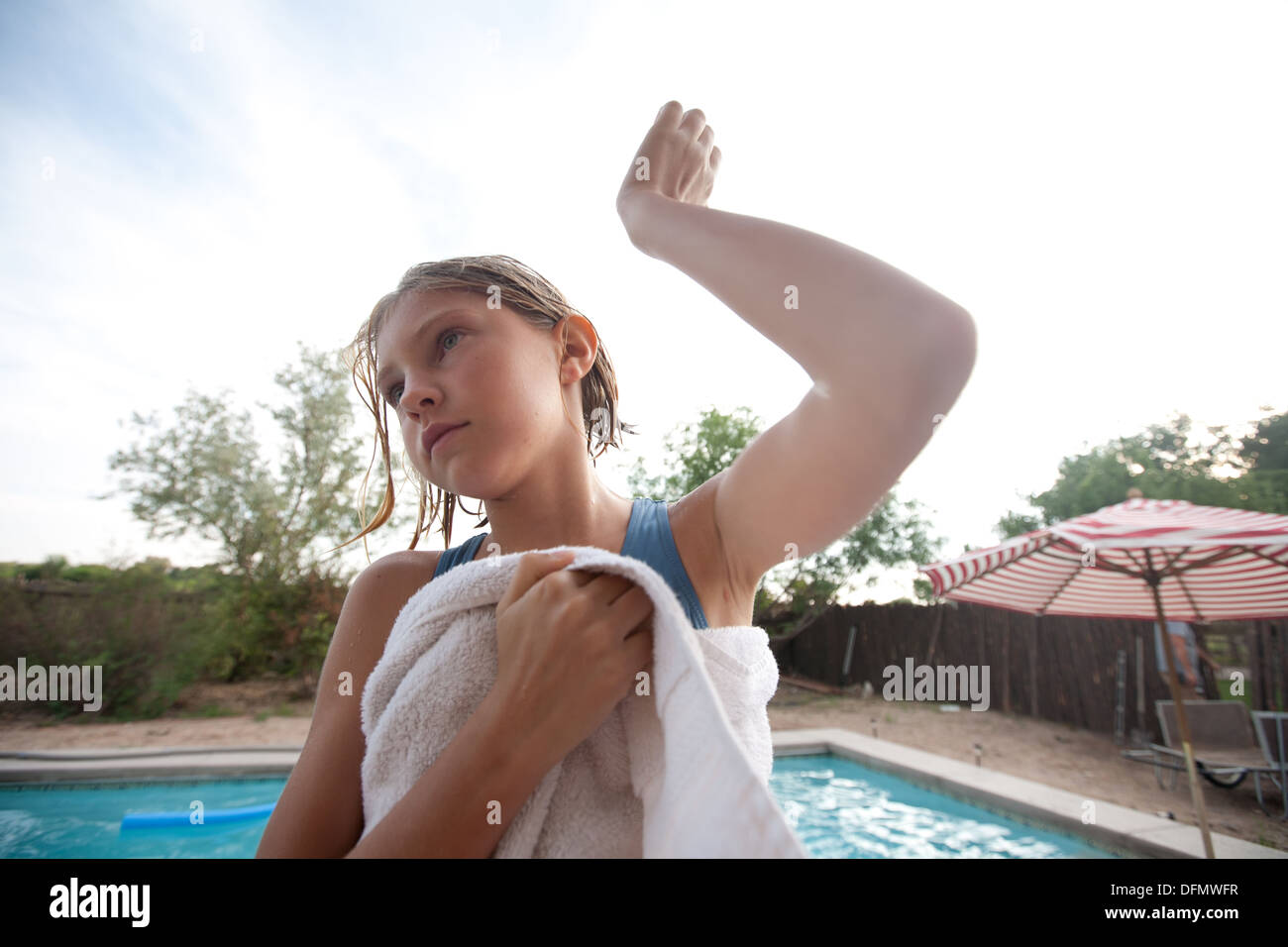 Dieci anni di scuotimento ragazza acqua fuori del suo orecchio dopo una nuotata all'esterno. Foto Stock
