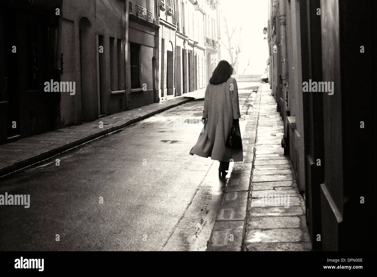 Elegante signora camminando lungo la strada umido nella mattina in anticipo sull'Île St Louis a Parigi Foto Stock